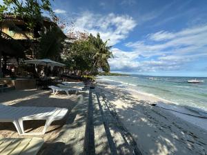 a beach with two white benches and the ocean at Pearl Resort Panglao,Dauis Bikini Beach in Dauis