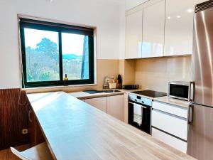 une cuisine avec des placards blancs et une grande fenêtre dans l'établissement Apartamento Samil Primera Línea de Playa 3A, à Vigo