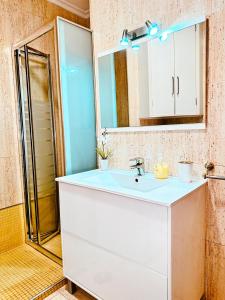 La salle de bains est pourvue d'un lavabo blanc et d'un miroir. dans l'établissement Apartamento Samil Primera Línea de Playa 3A, à Vigo