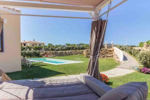 a patio with a couch and a swimming pool at Villa Cristallina Piscina privata, Wi-Fi & Netflix in Stintino