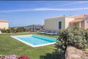 a backyard with a swimming pool and a house at Villa Cristallina Piscina privata, Wi-Fi & Netflix in Stintino