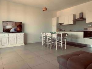 a kitchen with white cabinets and a table and chairs at Villa Cristallina Piscina privata, Wi-Fi & Netflix in Stintino