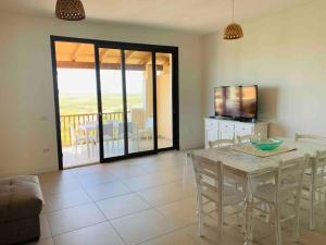 a dining room with a table and chairs and a television at Villa Cristallina Piscina privata, Wi-Fi & Netflix in Stintino