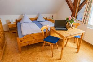 a bedroom with a bed and a desk with a laptop at Ferienhof Hofer in Absberg