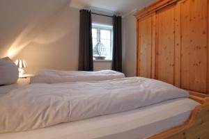 een slaapkamer met 2 witte bedden en een raam bij Starklef 29_ Whg_ 2 in Wyk auf Föhr