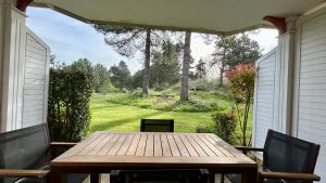 a wooden table on a porch with a view of a yard at Appartement avec terrasse vue sur le parc de golf in Fort-Mahon-Plage