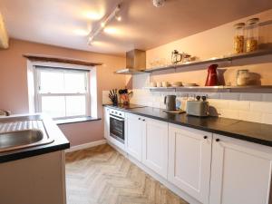 a kitchen with white cabinets and a sink and a window at The Loft at The Old Dog Thorpe in Ashbourne