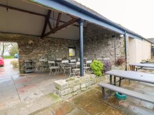 a patio with tables and chairs and a stone wall at The Loft at The Old Dog Thorpe in Ashbourne