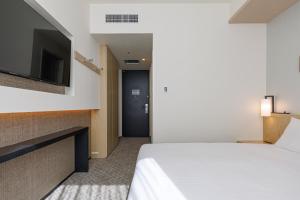 a hotel room with a bed and a flat screen tv at JR Kyushu Hotel Blossom Shinjuku in Tokyo