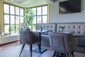 ein Esszimmer mit einem Tisch, Stühlen und Fenstern in der Unterkunft Hotel De Torenhoeve in Burgh Haamstede