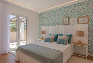 um quarto com uma cama com papel de parede azul e verde em Casa da Praia em Galé