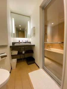 a bathroom with a shower and a sink and a tub at JR Kyushu Hotel Blossom Shinjuku in Tokyo