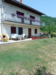 a house with a table and chairs in a yard at Apartman Lički san in Srb