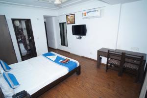Schlafzimmer mit einem Bett, einem Tisch und einem TV in der Unterkunft Hotel Laxmi Villa Palace in Jaipur