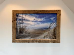 a picture of a beach in a wooden frame at Duinroos vlakbij strand in Egmond aan Zee