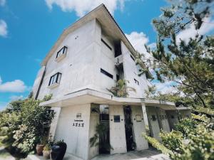 恩纳Hotel Condominium DOKADOKA的一座古老的白色建筑，上面种着植物