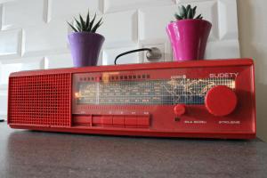 an old red radio sitting on a table with two plants at WSTApartments RetroFunky in Warsaw