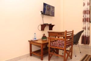 a desk with a chair and a wooden table with alevision at Pebbles guesthouse in Diani beach road in Ukunda