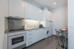 uma cozinha branca com um lavatório e uma máquina de lavar louça em GuestReady - Spacious modern stay in Porto em Vila Nova de Gaia