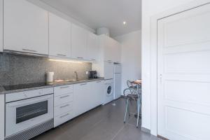 una cucina con armadi bianchi e piano cottura di GuestReady - Spacious modern stay in Porto a Vila Nova de Gaia