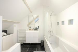 a white bathroom with a shower and a sink at The Doms Flats in Brussels