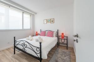 biała sypialnia z łóżkiem z czerwonymi poduszkami w obiekcie GuestReady - Retreat near Matosinhos beach w mieście Matosinhos
