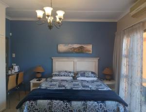 a bedroom with a bed with blue walls and a chandelier at SONHOS dreams Self catering apartment Unit 1 in Bloemfontein