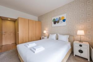 um quarto com uma cama branca com duas toalhas em GuestReady - Modern stay near Douro River no Porto