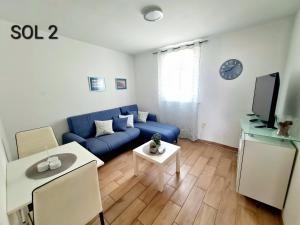 a living room with a blue couch and a tv at Apartments SOL in Izola