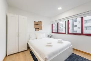 ポルトにあるGuestReady - Chic cityscape stayの白いベッドルーム(白いベッド1台、窓付)