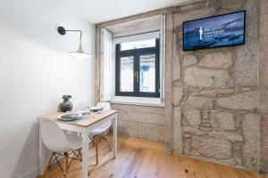 a room with a table and a tv on a stone wall at GuestReady - Private oasis for two in Porto +17 photos