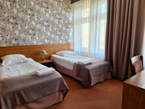 two beds in a hotel room with a window at Hotel Restauracja Rondo in Kutno