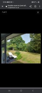een raam met uitzicht op een tuin met bomen bij The family room at the bungalow in Willesborough