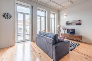 ein Wohnzimmer mit einem grauen Sofa und Fenstern in der Unterkunft GuestReady - Seaside getaway in Porto in Porto