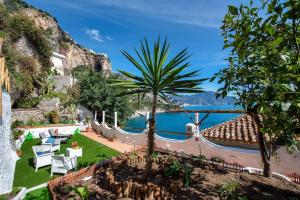a resort with a palm tree and a view of the water at L'Eden di Turo Brand New Loft in Conca dei Marini