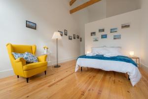 1 dormitorio con 1 cama y 1 silla amarilla en GuestReady - Quaint comfort near Clérigos Tower en Oporto