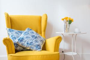 una silla amarilla con una almohada azul y blanca en GuestReady - Quaint comfort near Clérigos Tower en Oporto