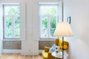 una sala de estar con una silla amarilla y ventanas en GuestReady - Quaint comfort near Clérigos Tower en Oporto