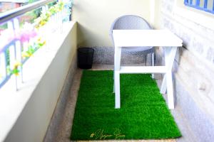 una mesa blanca y una silla sobre una alfombra verde en el balcón en Upper Haven Apartment, en Kakamega