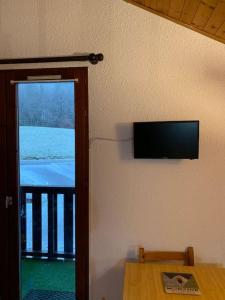 a room with a table and a television on the wall at Appartement plein sud montagne et lacs in Habère-Poche