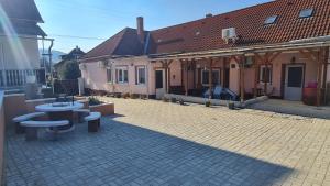 un patio con mesas y sillas frente a una casa en Pikoló Vendéglő és Vendégház en Bakonybél