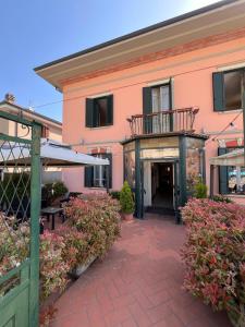 a pink building with a balcony and a patio at HOTEL LUDOVICO ARIOSTO in Castelnuovo di Garfagnana