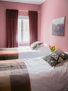 two beds in a room with pink walls and a window at Villa Loimu in Antskog