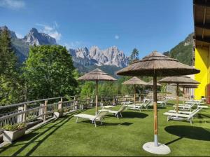 a row of chairs and umbrellas with mountains in the background at Bella Italia & EFA Village in Forni Avoltri