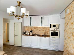 a white kitchen with white cabinets and a chandelier at R&R Apartament in Ocna-Mureşului