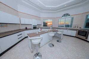 eine große Küche mit weißen Arbeitsflächen und Stühlen in der Unterkunft ST Beach Villa in Kibweni