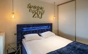 a bedroom with a bed with a blue headboard and lights at Apartamenty WRZOS w Perłowej Przystani in Sianozety