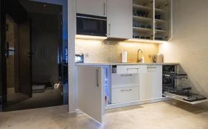 a kitchen with white cabinets and a sink at Apartamenty WRZOS w Perłowej Przystani in Sianozety