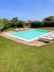 a swimming pool with lounge chairs next to a house at Villa Claudia piscina privata in Stintino