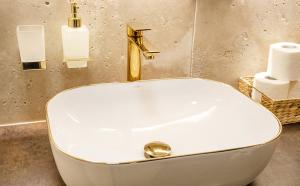 a bathroom with a white sink and a gold faucet at Apartamenty WRZOS w Perłowej Przystani in Sianozety